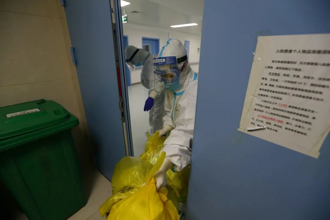 清晨，一名护士将夜里产生的医疗废物送出重症隔离区。（摄影：崔萌）