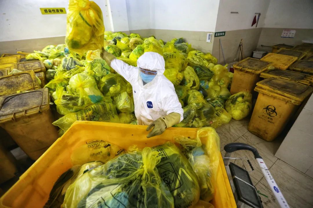 一名工人正在武汉同济医院中法新城院医疗废物暂存间工作。截止到记者发稿，该院区已将全部露天临时存放点的医疗废物清理完毕。（摄影：崔萌）