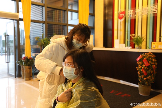 2月12日，一位医护人员在给同伴理发。她们都在武汉国际博览中心方舱医院工作。@张球球球球张