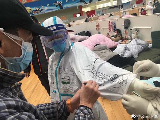 2月19日，武汉体育中心方舱医院，贵州医疗队队员邀请患者将贵州和武汉的美食、名胜古迹画在他们的防护服上。@文文小80