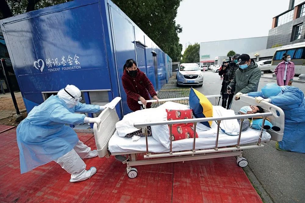 2月19日，武汉协和医院西院，两名护士艰难拖着病床上的一位重病患者前往CT室做检查。摄影/北京日报 和冠欣