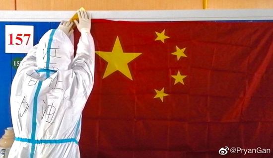 2月10日，武汉洪山体育馆方舱医院，江西医疗队的景颇族队员帕让甘鹏燃将国旗贴在墙上。@PryanGan