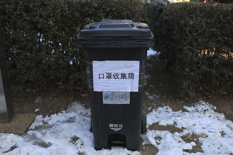 小区出口处设置专用的废弃口罩收集箱.小区门口拉起防控疫情条幅.