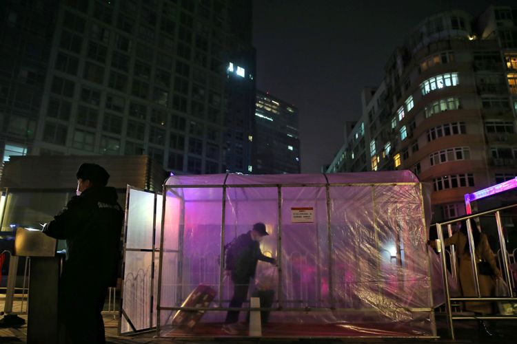 一位居民拖着行李从消毒棚内经过。