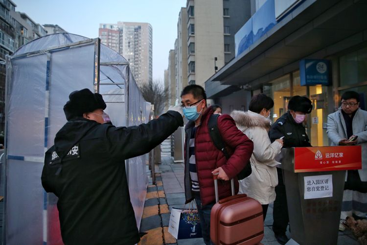小区保安为一位进小区的居民测量体温。