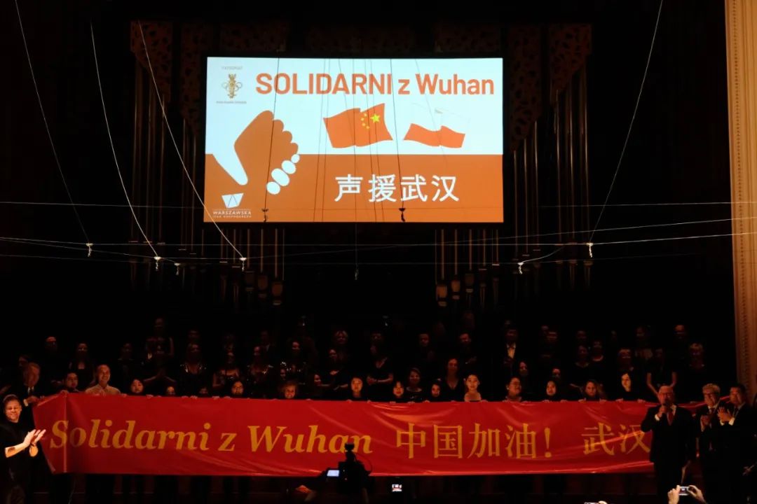 2月27日,在波兰国家爱乐音乐厅,演员们手举横幅为武汉加油.