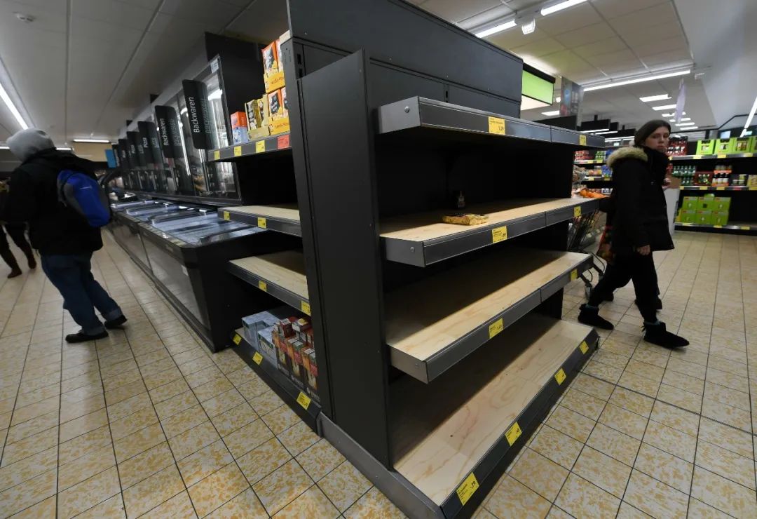  3月9日，在德国法兰克福一家超市，人们从空货架旁走过。新华社记者逯阳摄