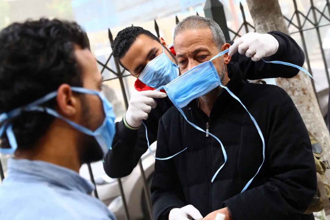 3月20日，在埃及开罗，志愿者帮助市民佩戴口罩。新华社发（艾哈迈德·戈马摄）