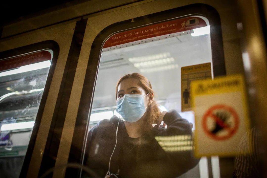 3月21日，新加坡市一名通勤途中戴着口罩做防护的年轻女性。
