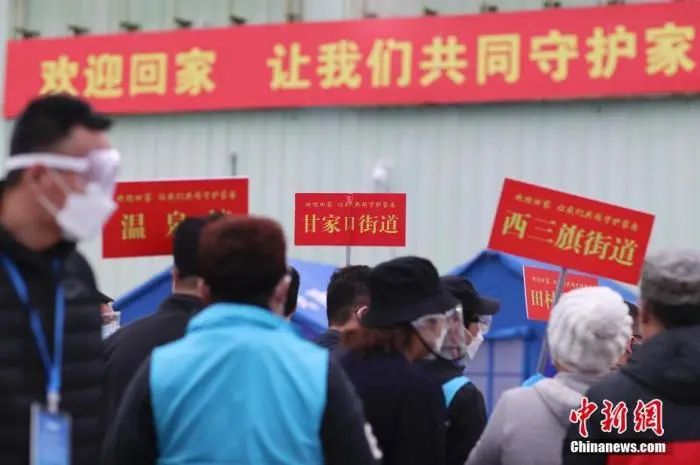 3月25日，北京市海淀区区级集中分流点，街镇工作人员举牌迎接离鄂返京人员抵达。