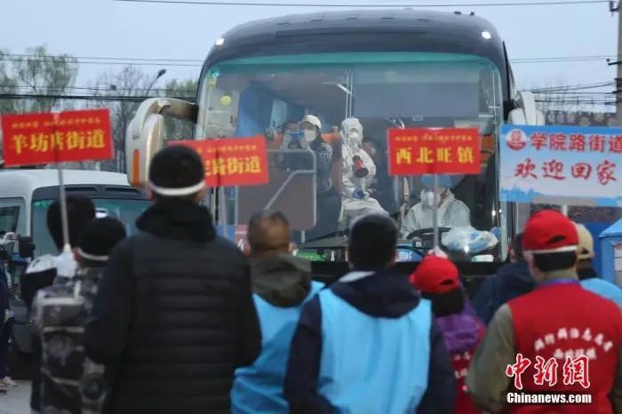  3月25日，北京市海淀区区级集中分流点，街镇工作人员举牌迎接离鄂返京人员抵达。