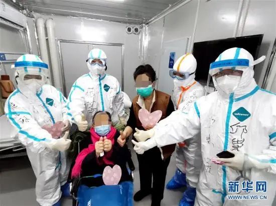 3月1日,98岁的新冠肺热危重症患者胡婆婆(坐轮椅者)和女儿出院时,与武汉雷神山医院医护人员相符影(手机拍摄)。高翔 摄 图片来源:新华网