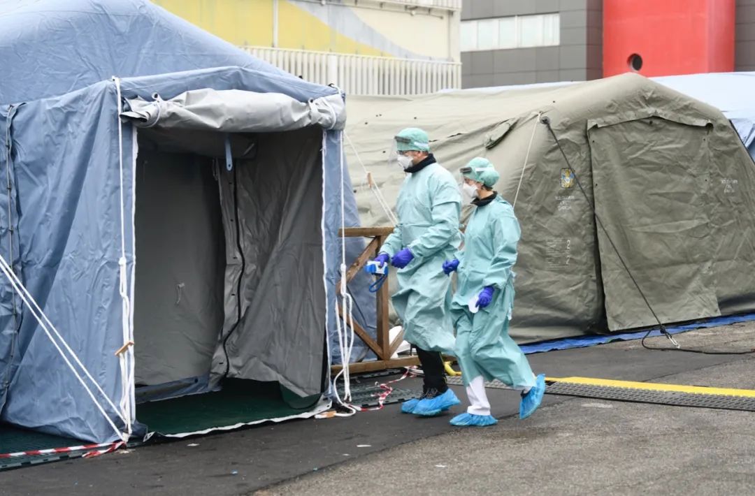 3月3日，在意大利布雷西亚，医务人员进入在医院外搭建的帐篷（图片来源：新华社）