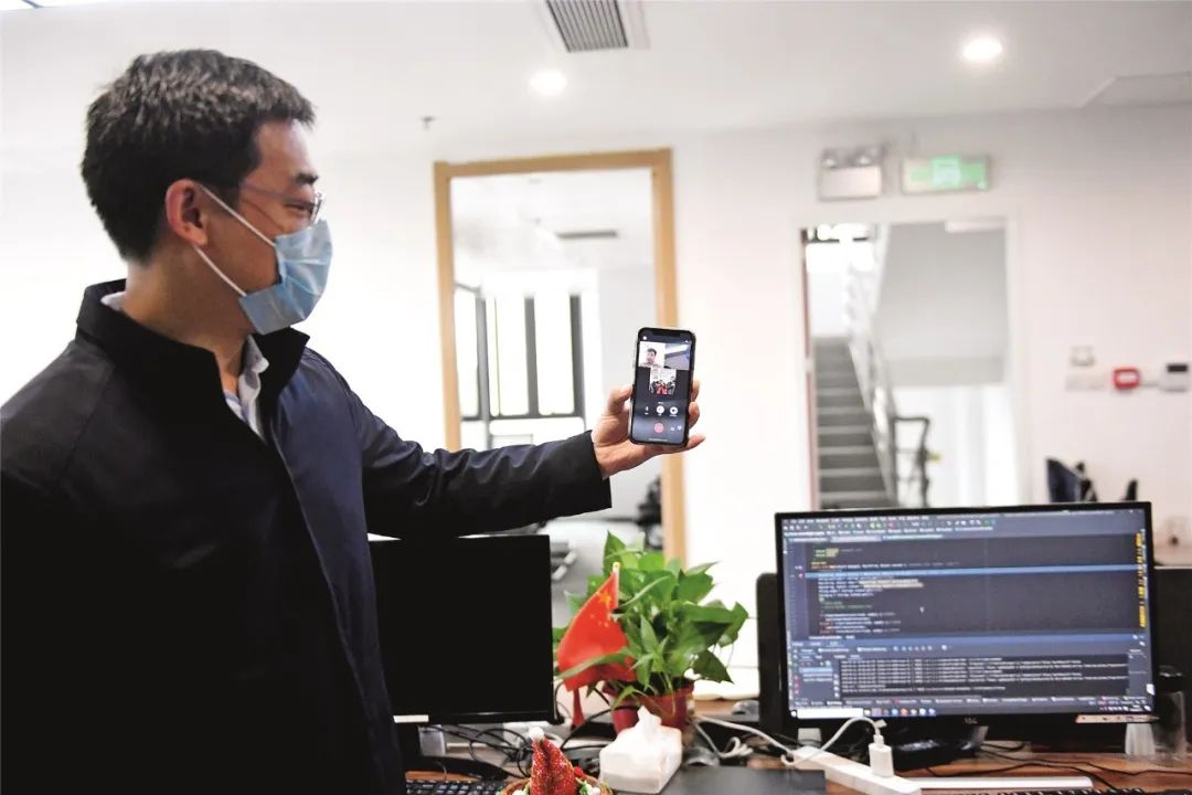 2月11日,位于广州南沙区锦珠广场的中科智城(广州)信休科技有限公司内,空无一人的办工位上几台电脑正在运走,表现器上的代码往往起伏。该企业的技术研发人员正远在家中,经过网络连接长途操作公司电脑,实现在线办公。图为该公司研发部副总监吴鸿与同事在线疏导。摄影/本刊记者 姬东