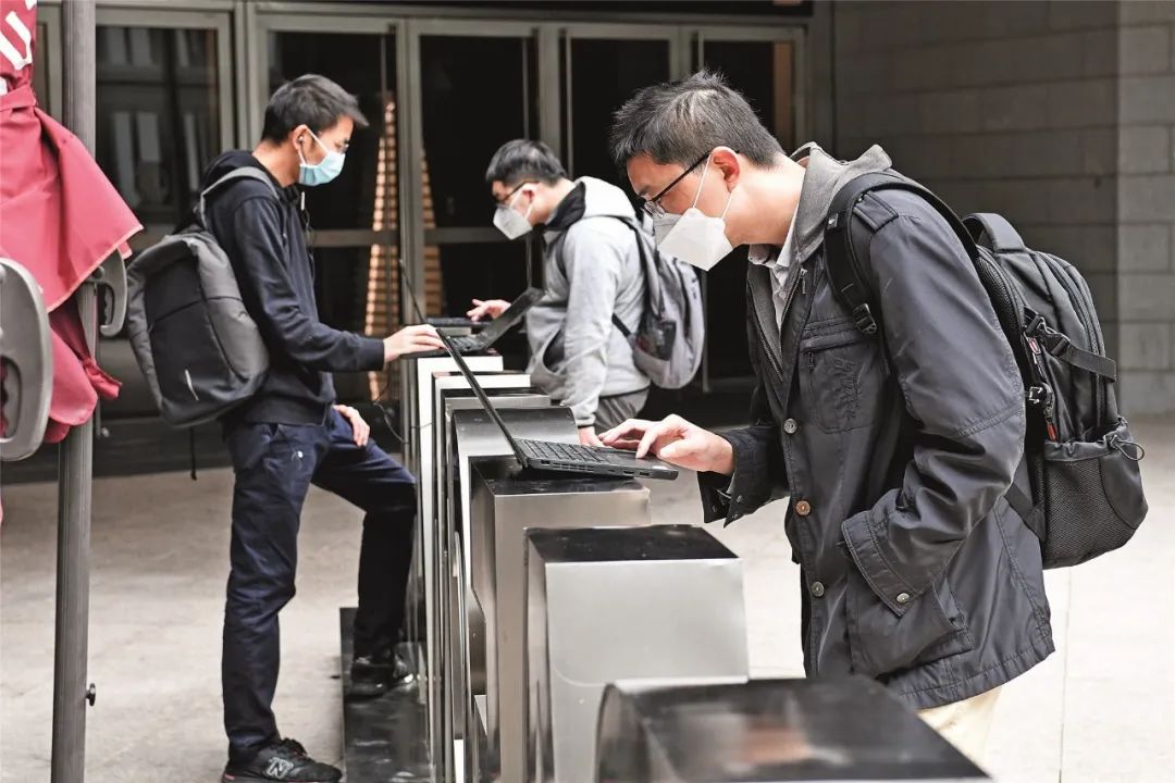 2月10日,在深圳坦然金融中央,企业员工在楼下行使笔记本电脑连接公司内网下载安设长途办公柔件,以便实现居家“云办公”。图/新华