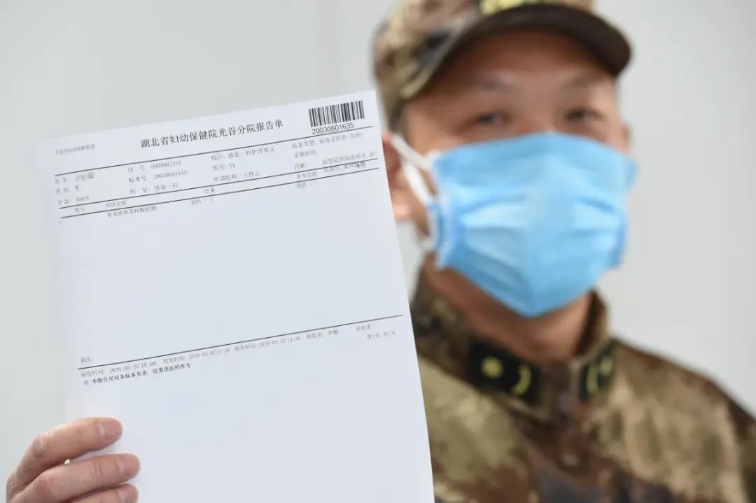 医务人员向记者展示老人的新冠病毒核酸检测阴性报告单 摄影：赵佳庆