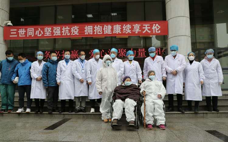 时荣祖孙三人从武汉市第一医院康复出院时，与医护人员合影留念。受访者供图