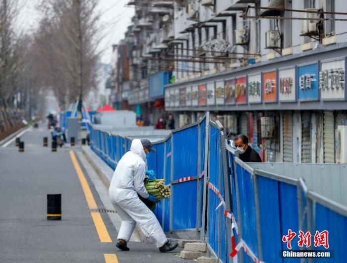 3月6日，武汉汉阳鹦鹉大道，志愿者正在给居民送生活物资 。中新社记者 张畅 摄