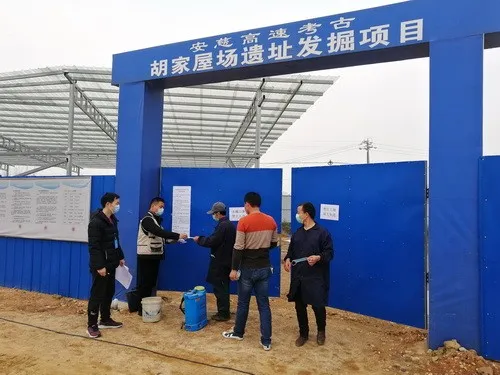 湖南基建考古项目工地门口，工作人员在给进场人员发放口罩等防疫物资。