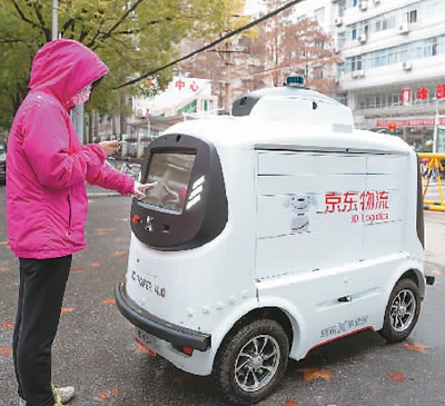 在武汉市第九医院，患者家属从智能配送机器人上取快件。