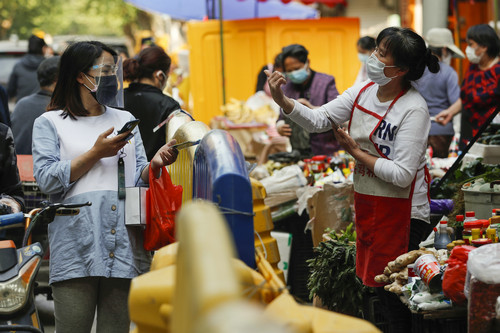 资料图片：4月16日，人们在武汉街边购买新鲜蔬菜、调料等。新华社