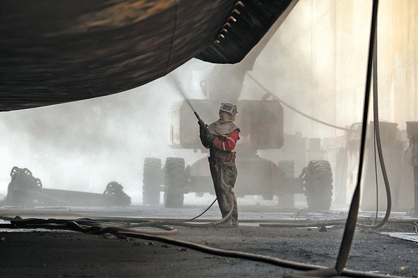 "海洋石油230"船体外,两名打砂工专心作业,栈桥上搬运物资的施工人员