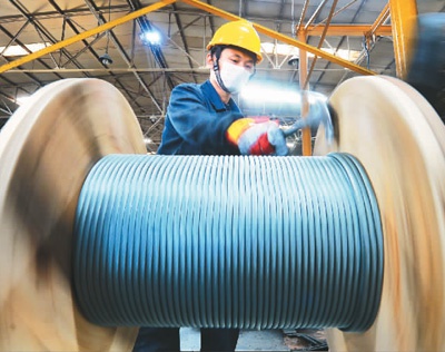 4月21日，一名工人在青岛迪世亚制钢有限公司车间里进行钢丝绳卷取作业。王海滨摄（人民图片）