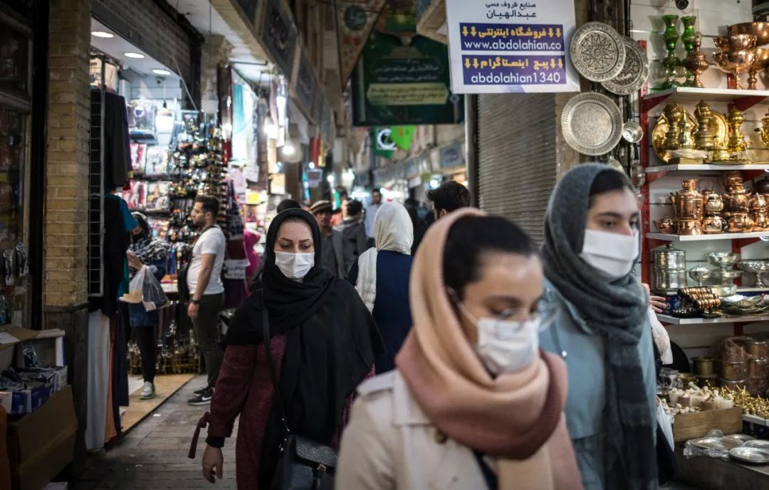 4月24日，在伊朗德黑兰，戴着口罩的市民经过集市。新华社发（艾哈迈德·哈拉比萨斯摄）