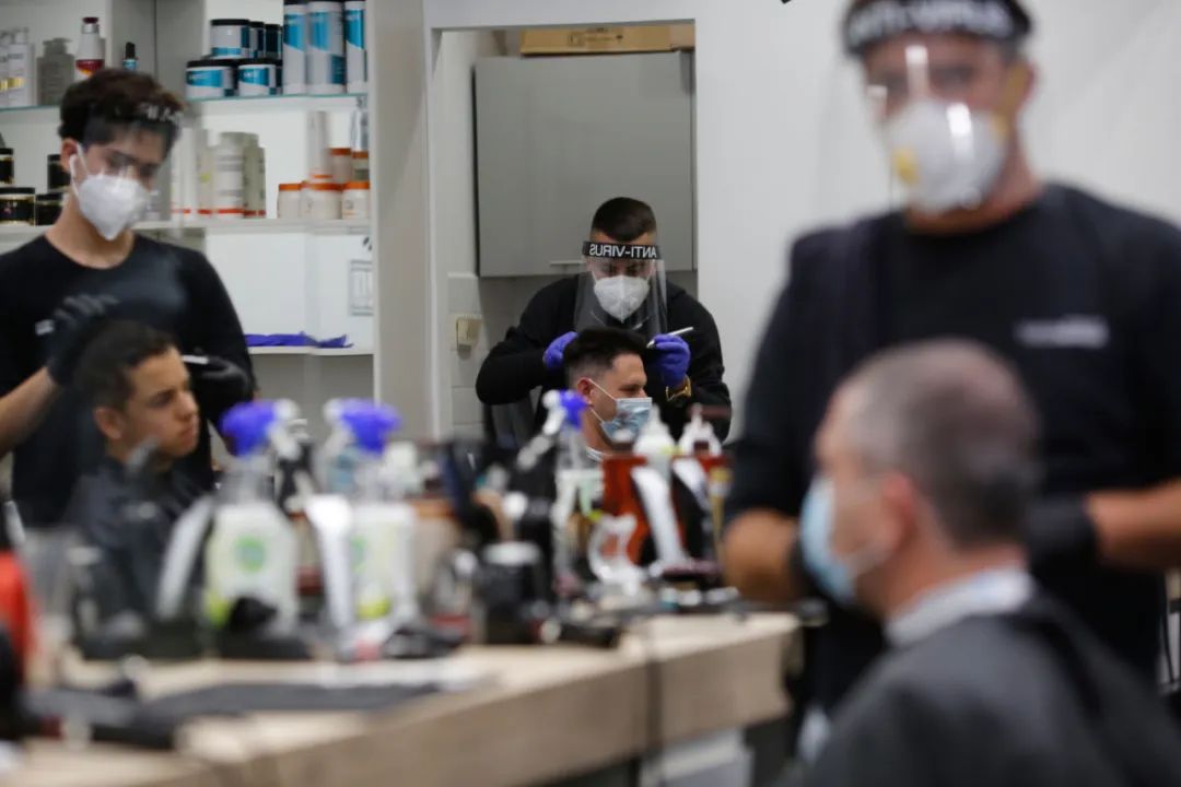 4月26日，在以色列中部城市莫迪因的一家理发店内，理发师在为客人理发。新华社发（吉尔·科恩·马根摄）