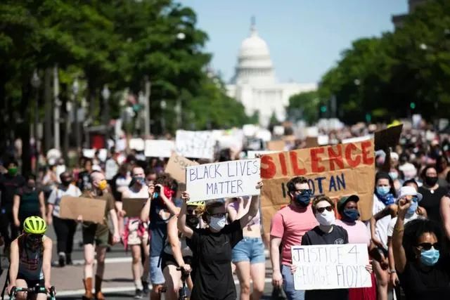  5月30日，在美国首都华盛顿国会山附近，人们手持标语参加抗议活动    摄 | 刘杰（新华社）