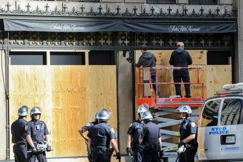  6月1日，在纽约曼哈顿第五大道，工人为一家高端百货公司加装木板。新华社记者 王迎 摄