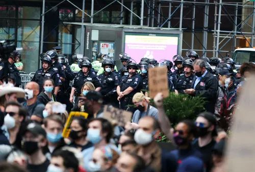  6月1日，在美国纽约时报广场，警察在抗议者附近警戒。新华社记者 王迎 摄