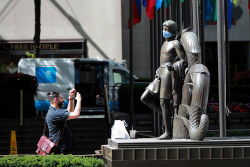 6月22日，在美国纽约洛克菲勒中心，一名男子拍摄“戴”口罩的雕像。新华社记者 王迎 摄