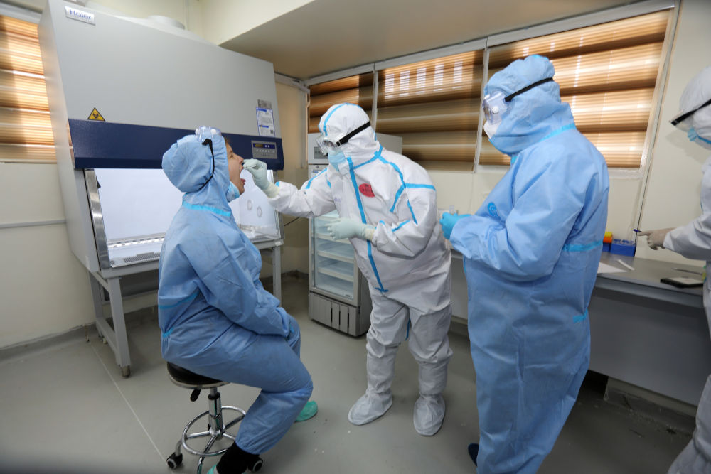 3月26日，在位于伊拉克巴格达的中国援建伊拉克核酸检测实验室，中国援助伊拉克防治新冠肺炎医疗专家组成员杨鸿辉（中）取咽拭子。新华社发