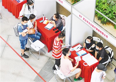 6月1日，一场大型招聘会在江汉大学校园举办，这是疫情发生后武汉举办的首场高校毕业生专场线下招聘会。武汉市人社部门从报名企业中遴选了80多家企业参加，专门招聘高校毕业生。图为求职者在招聘会上与招聘人员洽谈。