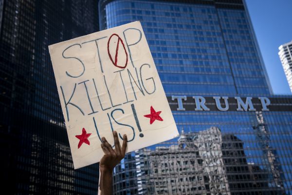  5月30日，在美国芝加哥的特朗普大厦前，一名示威者高举抗议标语。（新华社））