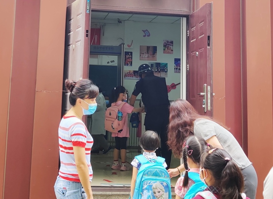 北京十八中附属实验小学的新生们排队等待手部消毒、测体温进校。