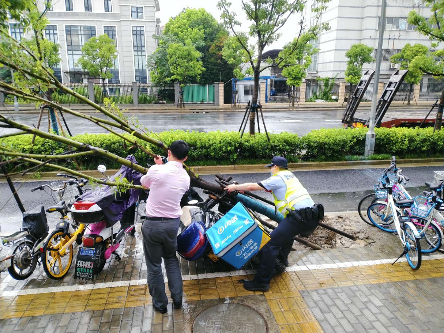 闵行公安莘庄派出所民警汪皓正在闵松路中春路路口清理被台风刮落影响交通的树枝