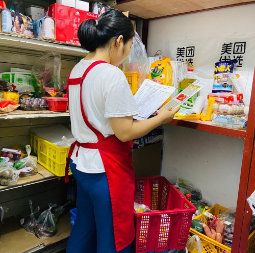 (美团优选社区团购团长刘敏在储藏室收货)