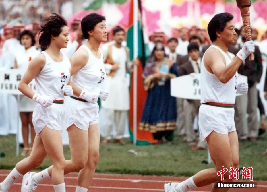 资料图：1990年9月22日，第11届亚运会开幕式上，中国射击运动员许海峰手持火炬与跳水运动员高敏、女排名将张蓉芳一起入场，点燃亚运会主火炬。中新社记者 任晨鸣 摄