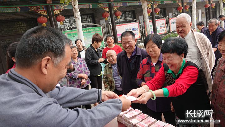 东街村"两委"干部为60岁以上老人发放养老金,老人拿到养老金后笑得合