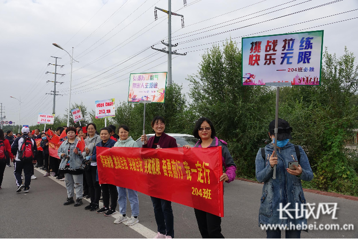 远足途中,家长们举起条幅为孩子们加油打气.