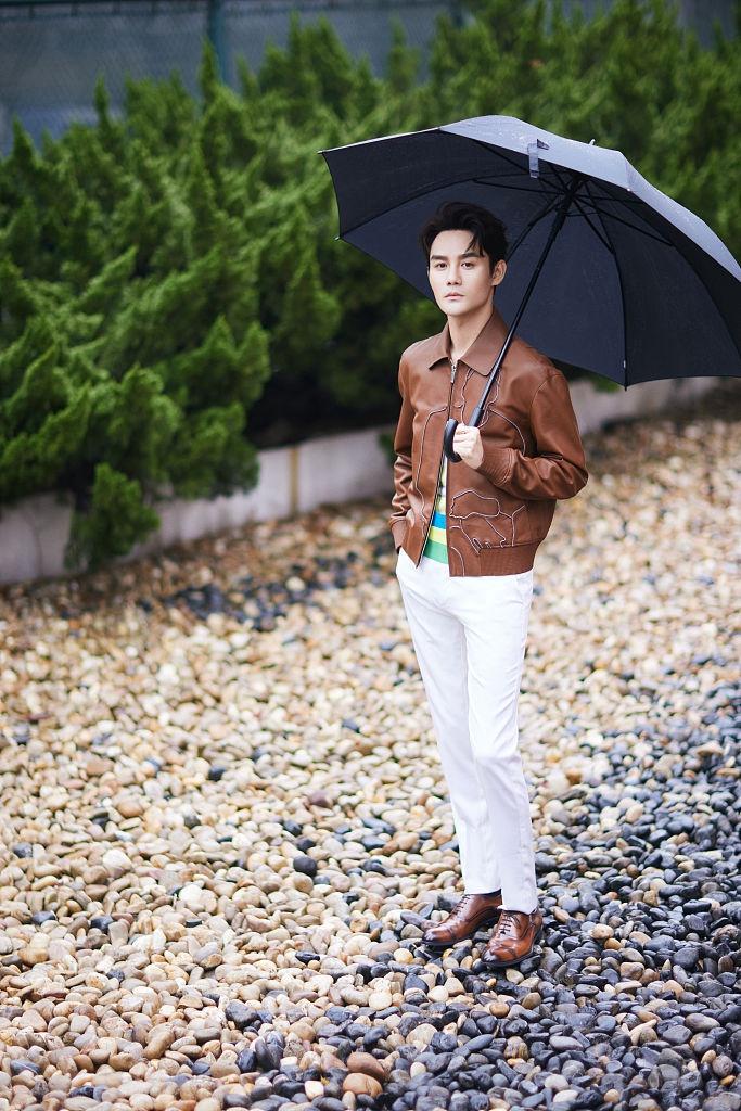 王凯穿复古皮衣化身儒雅君子 打伞扮酷尽显洒脱气质