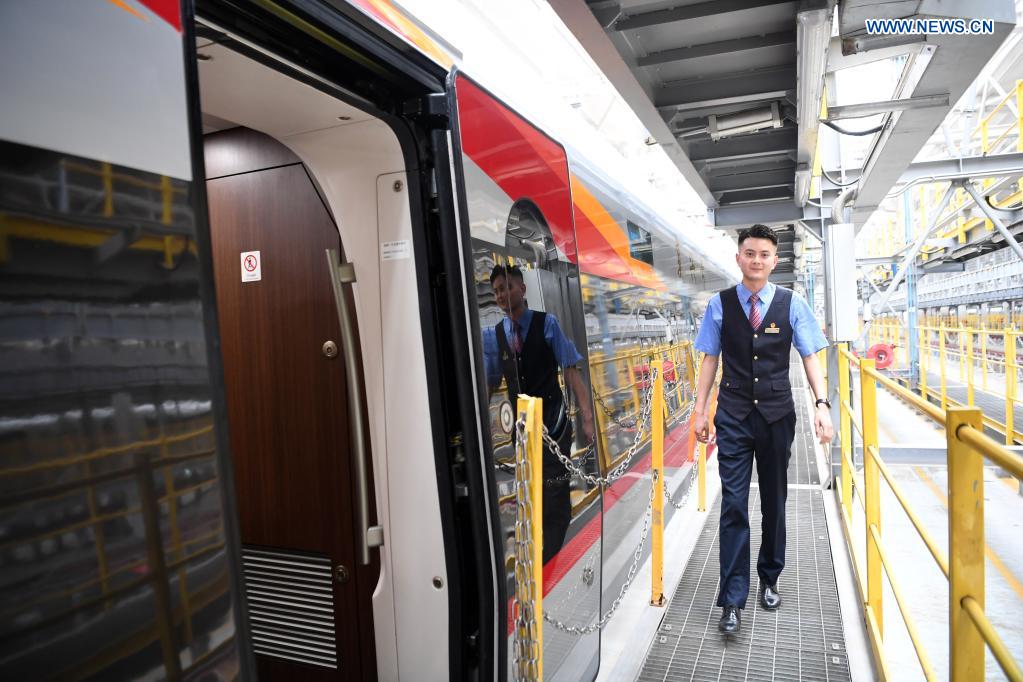 A crew member walks past a CR400AF Fuxing intelligent bullet train in southwest China's Chongqing, June 23, 2021. The CR400AF Fuxing intelligent bullet train will be put into service on the railway linking Chengdu, capital city of southwest China's Sichuang Province, and Chongqing on Friday. (Xinhua/Tang Yi)