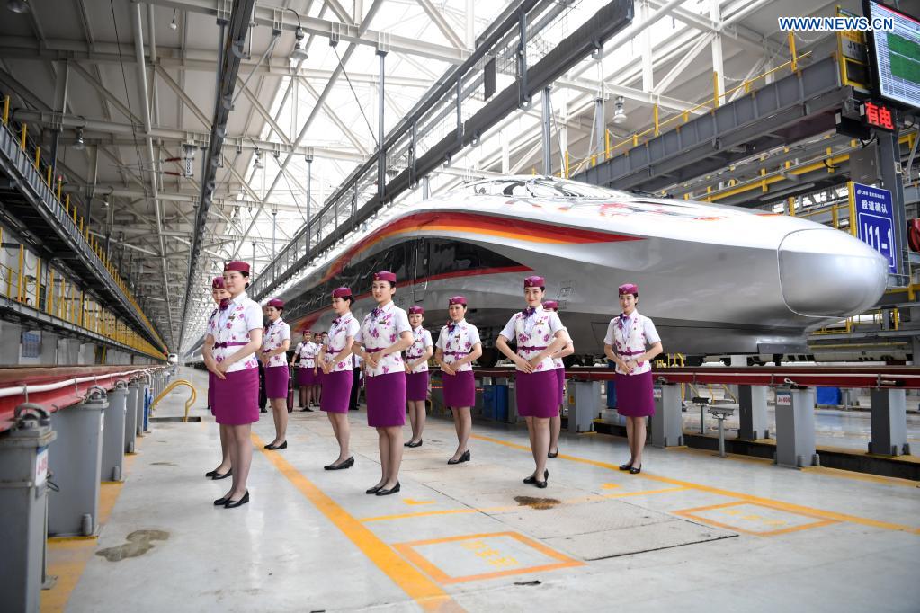 Crew members pose for photos with a CR400AF Fuxing intelligent bullet train in southwest China's Chongqing, June 23, 2021. The CR400AF Fuxing intelligent bullet train will be put into service on the railway linking Chengdu, capital city of southwest China's Sichuang Province, and Chongqing on Friday. (Xinhua/Tang Yi)