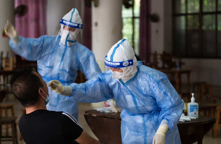 △18日，云南省瑞丽市勐卯镇一核酸检测点，核酸检测人员正在进行咽拭子采集工作。