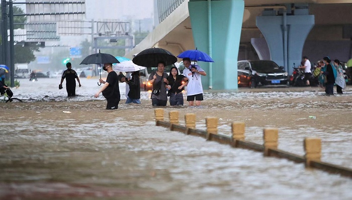 郑州市民走在齐腰深的积水里。图片来源：视觉中国