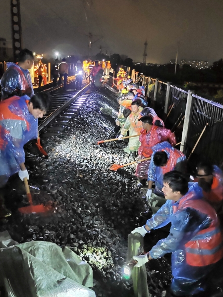 图为中铁电气化局员工连夜冒雨装填沙袋