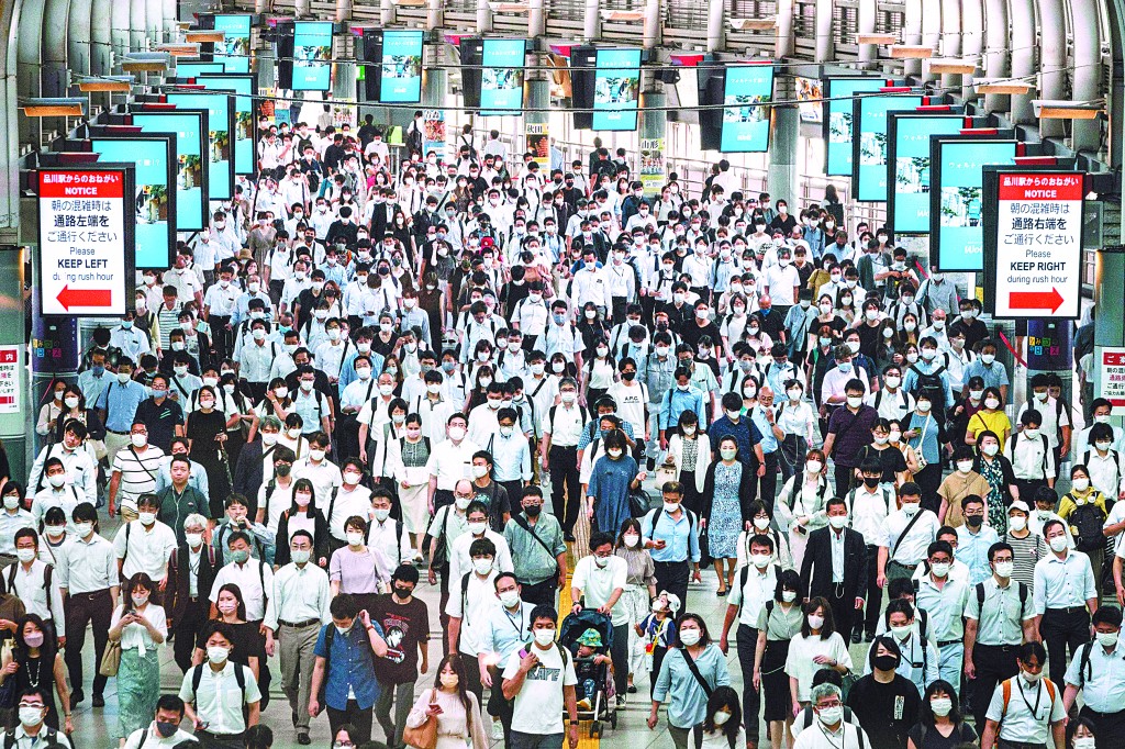 28日下午，东京都公布当日新增新冠肺炎确诊人数达3177人，连续第二天刷新历史纪录。图为当天，东京一处火车站戴着口罩的通勤者。