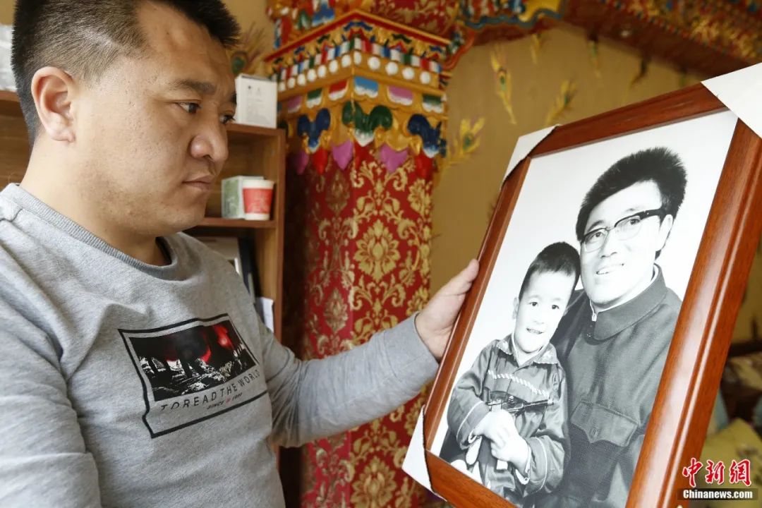 图为索南达杰次子索南旦正举着父亲和哥哥的合照 张添福 摄
